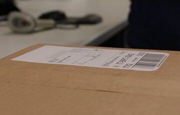 A label sits on the surface of a cardboard box.