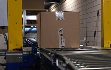 A cardboard box moving on a conveyor belt.